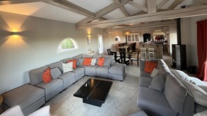 A spacious living area with a large grey sectional sofa, a black coffee table, and a kitchen in the background. - Villa Théia (Flayosc)