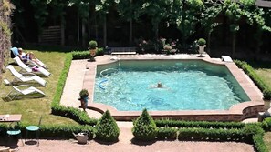 A rectangular swimming pool surrounded by a brick border, with lounge chairs and a small garden area with trimmed bushes. - Chateau La Servayrie (Conques-en-Rouergue)