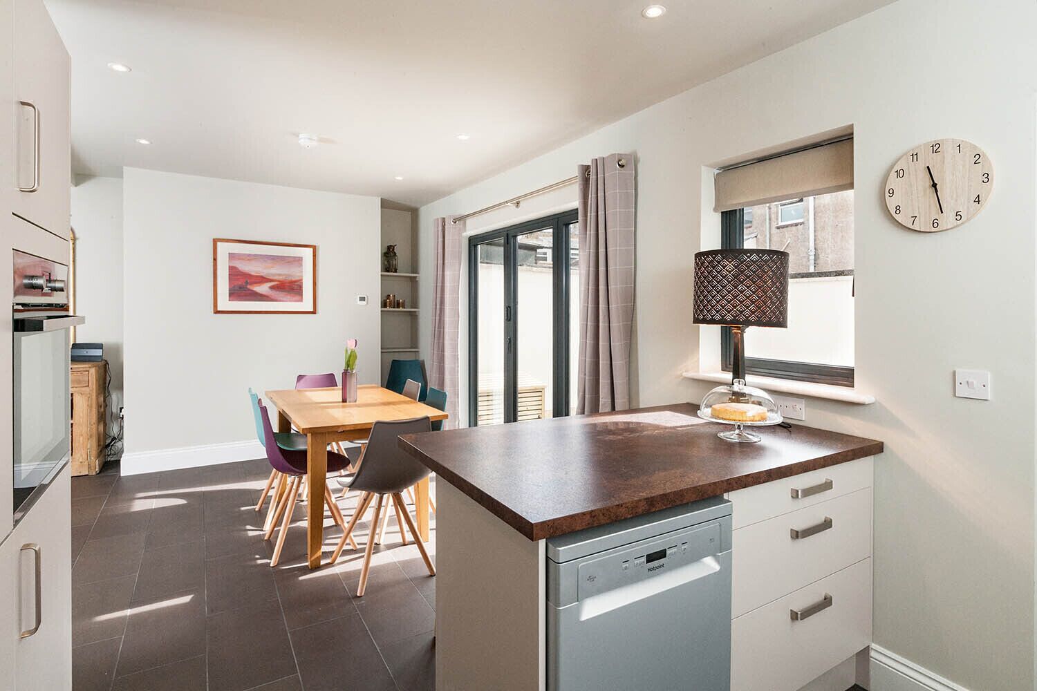 A modern kitchen with a wooden countertop, a dishwasher, and a dining area with a table and chairs.