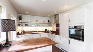 Una cocina moderna con armarios blancos, horno de acero inoxidable y encimera de madera.