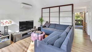A modern living room with a sectional sofa, a flat-screen TV, a coffee table, and a wooden floor. - Ren Basera - Minutes from the base of Mt Buller (Sawmill Settlement)