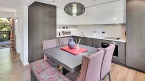 A modern kitchen with grey cabinets, a central island, and a dining area with a table and chairs. - Ren Basera - Minutes from the base of Mt Buller (Sawmill Settlement)