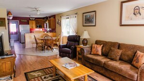 Una sala de estar amplia con una mesa de centro de madera, un sofá de cuero marrón y un comedor con una mesa y sillas de madera.