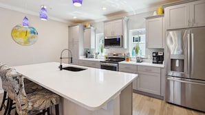 A modern kitchen with a central island, stainless steel appliances, and pendant lighting. - Lost Key Golf & Beach Club Townhome -Make Waves ~  NO HASSLE CHECK OUT (Perdido Key)