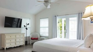 A bedroom with a bed, a dresser, a TV, and a ceiling fan.