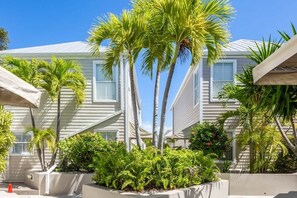 A coastal hotel with multiple-story buildings, palm trees, and a well-maintained garden.
