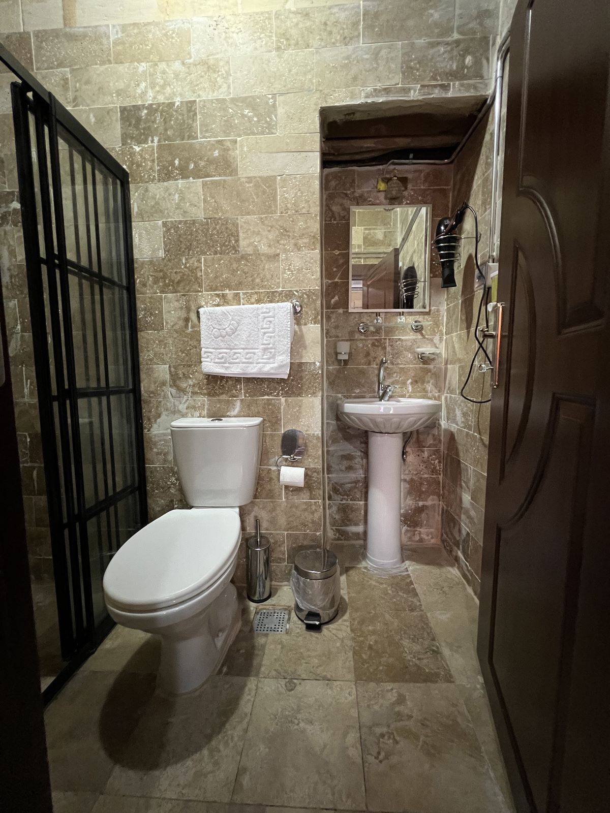 A compact bathroom with a toilet, sink, and mirror.