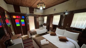 A hotel room with two beds, a small kitchenette, a window with curtains, and a ceiling fan. - Gökhan Bey Konağı  (Gaziantep)