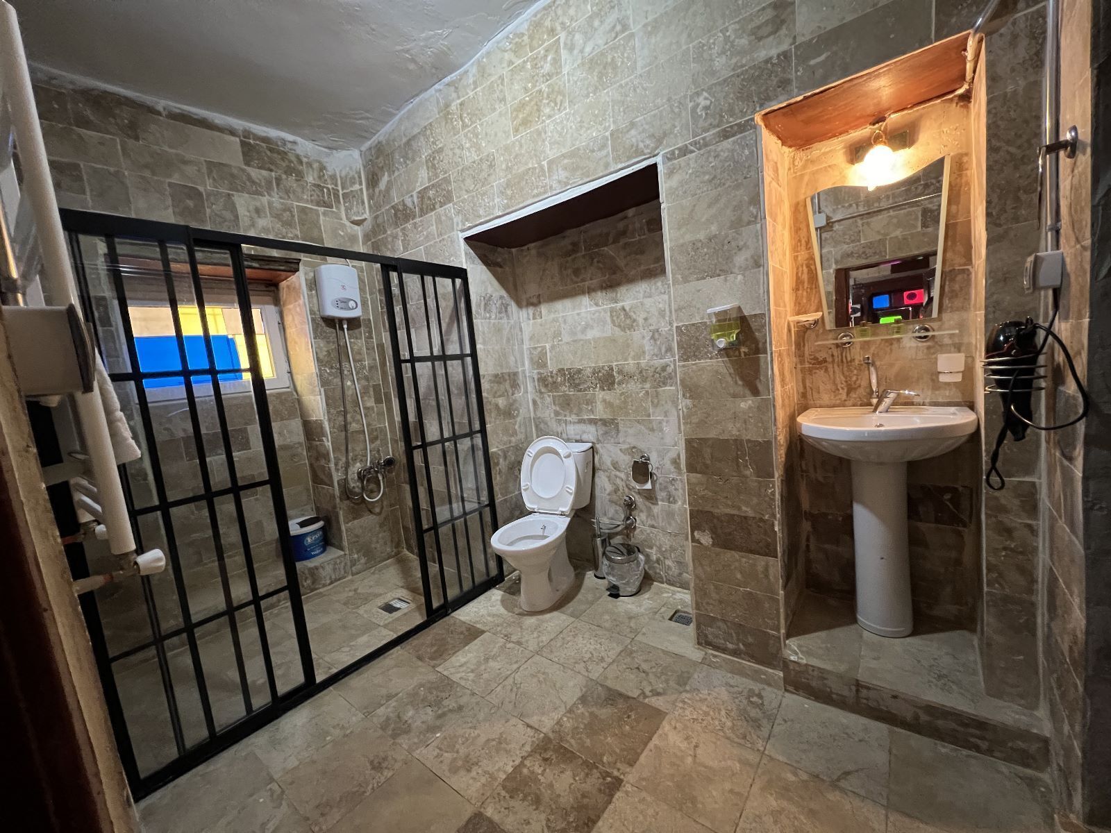 A bathroom with a toilet, sink, and shower area.
