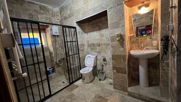 A bathroom with a toilet, sink, and shower area.