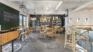 Ein Restaurantinneres mit einer Kreidetafel, Korbmöbeln und einem Schild mit der Aufschrift 'EAT'.