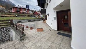 Une cour dallée de pierres, agrémentée de plantes en pot, et un bâtiment sur lequel on peut lire l’inscription « La ».