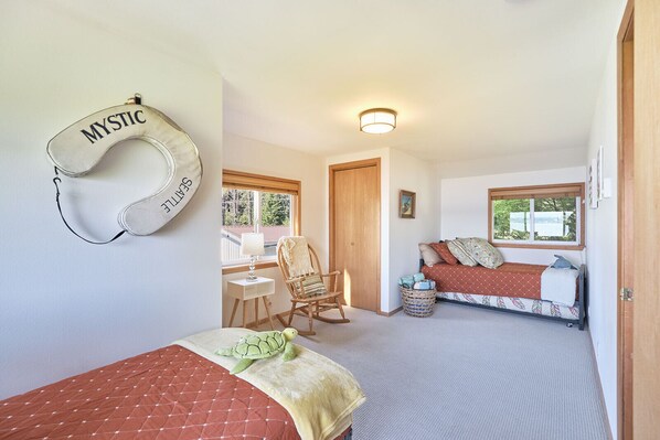 A cozy bedroom with a bed, a rocking chair, a turtle plush toy, a basket, and a wall-mounted headboard with the word "MYSTIC".
