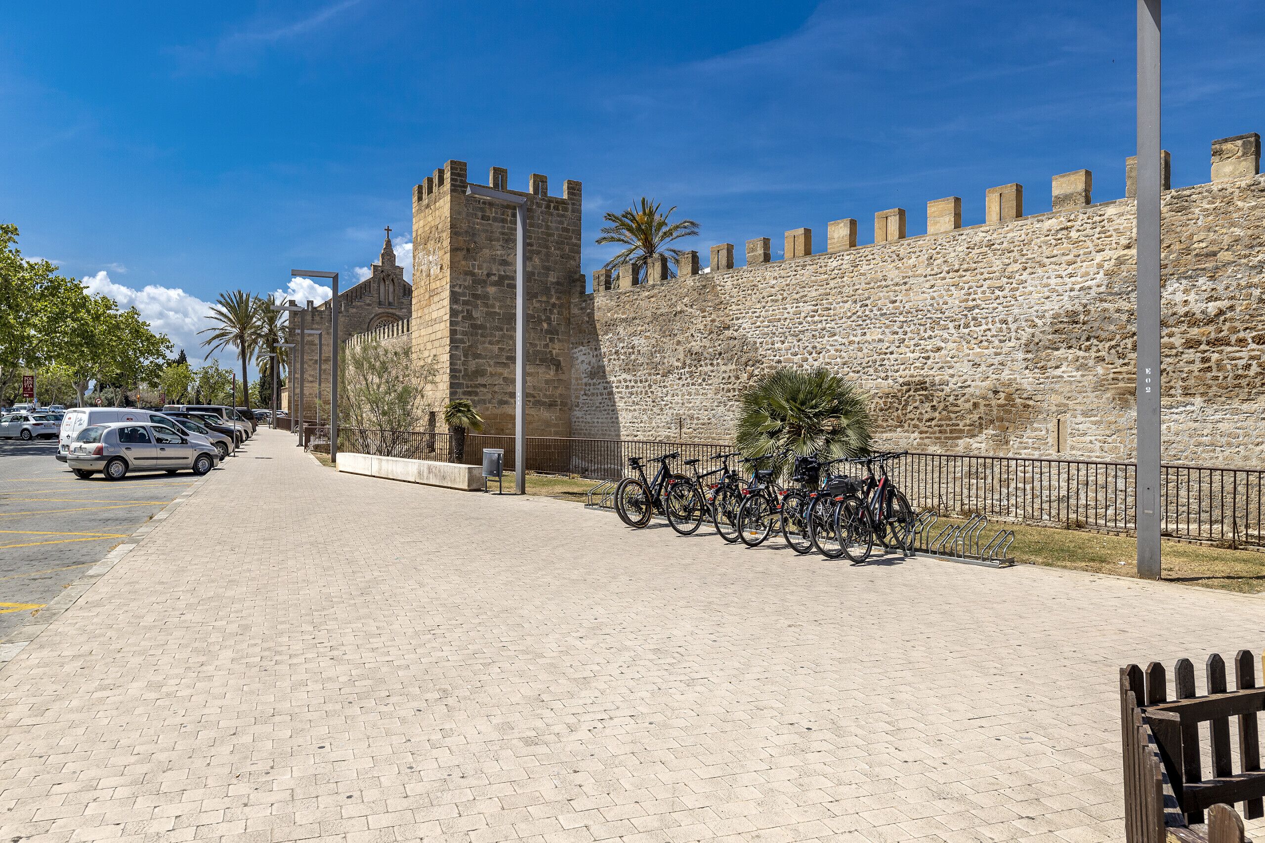 A paved walkway with a stone wall and a tower.