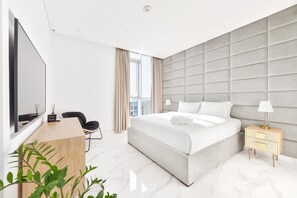 Ein modernes Hotelzimmer mit einem großen Bett, einem Schreibtisch, einem Sessel und einem Fernseher.