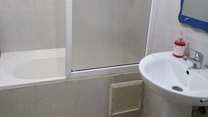 A bathroom with a bathtub, a shower enclosure, a sink, and a mirror. - Family apartment 07 (Marrakech)