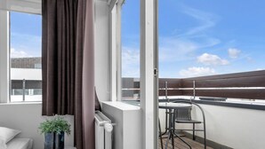 A balcony with a table and chair, a potted plant, and a view of the cityscape. - Svala Downtown Studio (Reykjavík)
