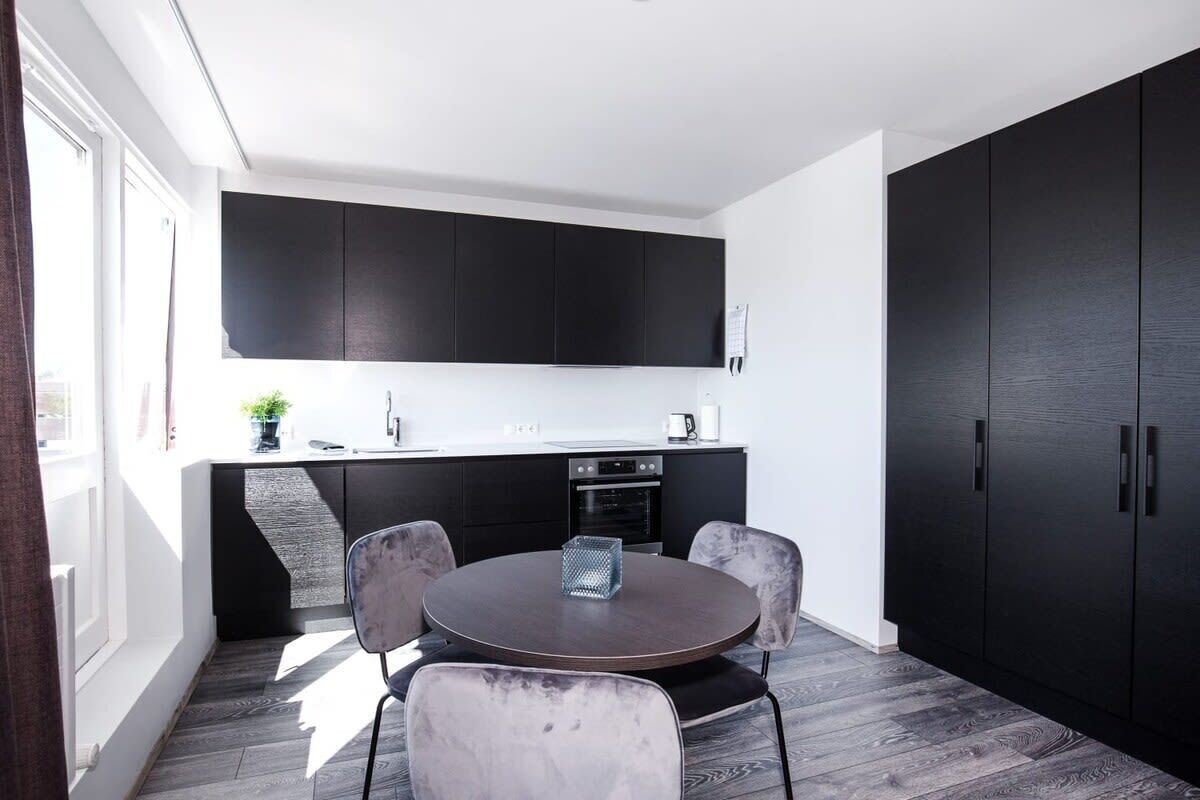 A modern kitchen with dark cabinets, a round dining table, and four chairs.