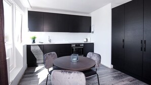 Une cuisine moderne avec des meubles de rangement de couleur sombre, une table de salle à manger ronde et quatre chaises.