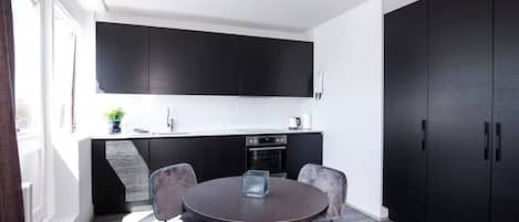 Une cuisine moderne avec des meubles de rangement de couleur sombre, une table de salle à manger ronde et quatre chaises.