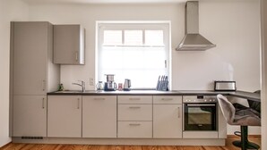 A modern kitchen with a window, stainless steel appliances, and a built-in oven.