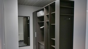 A walk-in closet with multiple shelves and drawers, a mirror, and a radiator.