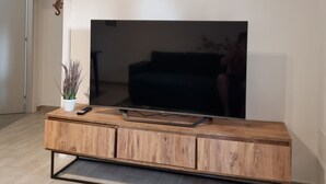 Una sala de estar moderna con un televisor de pantalla plana grande montado sobre una consola de madera, debajo de un arco y flecha decorativos fijados a la pared.