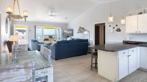 Ein geräumiger Wohnbereich mit einem blauen Sofa, eine Küche mit weißen Schränken und eine Essecke mit einer Bar.