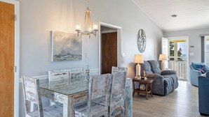 Ein Essbereich mit einem Glastisch und Stühlen, einer Chandelierleuchtre und einem Gemälde an der Wand.