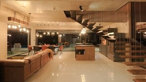 A modern interior with a central island, seating area, and a staircase.