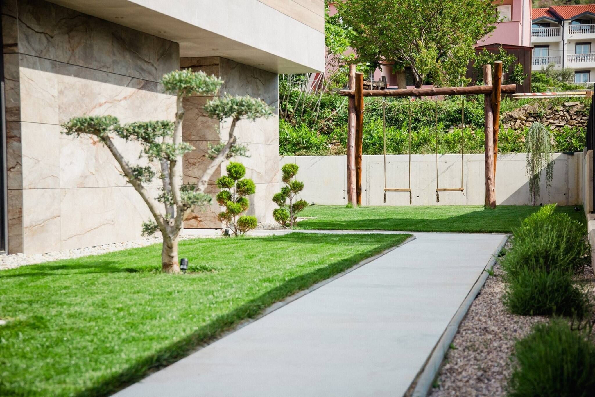 Un bâtiment moderne avec un chemin pavé, une pelouse bien entretenue et de jeunes arbres.