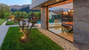 A modern house with a swimming pool, outdoor seating, and a view of mountains. - Luxury Villa Krk Baska II with Heated Pool (Baska)