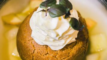 A dessert in a bowl with a dollop of cream and a leaf garnish.