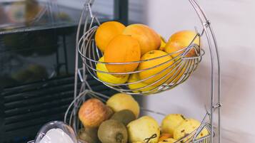 A fruit stand with oranges and kiwis, and a juicer on a table.