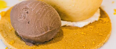 A dessert with a scoop of chocolate ice cream and a scoop of vanilla ice cream on a plate with a yellow garnish.