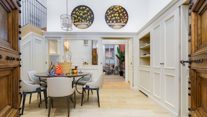 A dining area with a round table and chairs, a hanging light fixture, and a view into another room with a plant. - Visconte Filippo - La Dimora degli Affreschi Florence (Florence)