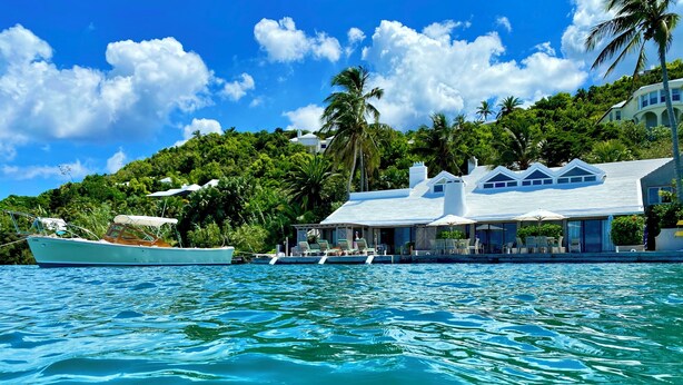 A waterfront property with a boat dock, a pool area, and lush greenery. - Luxury Waterfront Home on Harrington Sound in Smith's Parish (Flatts Village)