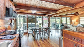Un'ampia cucina con mobili in legno, un'area pranzo con sedie e un'ampia finestra che offre vista sull'esterno.