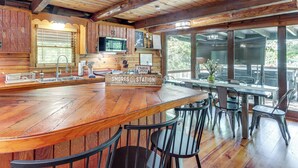 Un interno rustico in legno con un'area bar, una sala da pranzo e una cucina con forno a microonde.