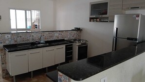 A kitchen with a tiled backsplash, a gas stove, a refrigerator, and a window with bars. - House with pool and huge backyard for children!!! (Peruíbe)