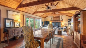 A spacious dining area with a wooden table and chairs, a ceiling fan, and a view of the outdoors through large windows. - Hot Tub + Fire Pit | Vineyard Near Templeton + Paso | Vineyard Retreat (Templeton)