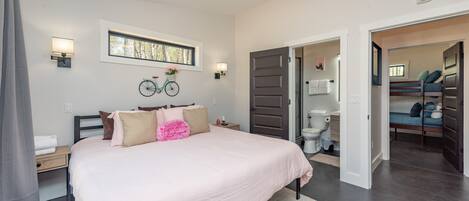 Un dormitorio con una cama grande, un ventilador de techo, una ventana y una bicicleta decorativa en la pared.
