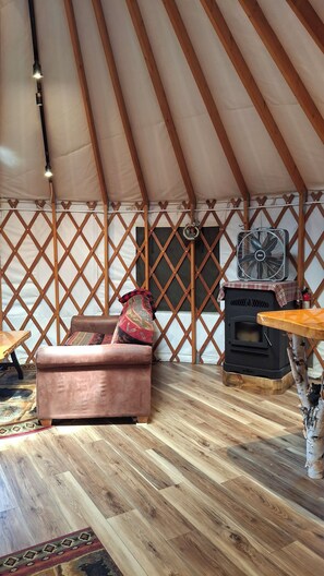 Un intérieur chaleureux avec un canapé, une table, un ventilateur et un poêle à bois.