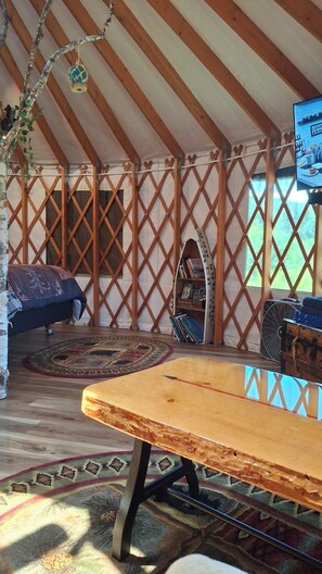 Un espace confortable et intime, doté d’un plafond en bois, d’un canapé, d’une table et d’un téléviseur.