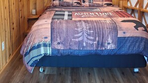 Una habitación de madera con una cama, un estante en la pared y una planta colgante.
