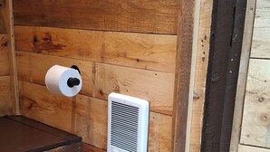 A wooden cabin interior with a toilet, a roll of toilet paper, and a vent. - Redarrow rustic yurt  in the Adirondacks,  Gore Mt. 15 mins, jug water supplied (Minerva)