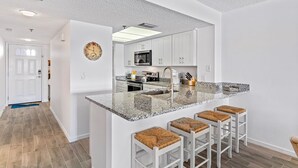 A modern kitchen with a granite countertop, white cabinetry, and a built-in microwave. - Intercoastal Waterway-Amazing Condo-Heated Pool (Indian shores)