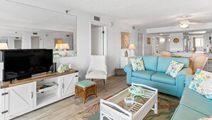 A modern living room with a flat-screen TV, a sofa, a chair, and a dining area. - Intercoastal Waterway-Amazing Condo-Heated Pool (Indian shores)