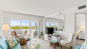 A spacious living room with a balcony, a television, and a comfortable seating area. - Intercoastal Waterway-Amazing Condo-Heated Pool (Indian shores)