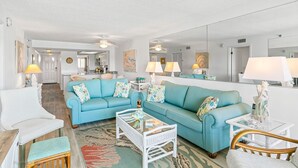 A spacious living room with two blue sofas, a white coffee table, and a dining area with a white table and chairs. - Intercoastal Waterway-Amazing Condo-Heated Pool (Indian shores)